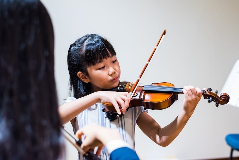 A young student concentrating as she plays the violin. 